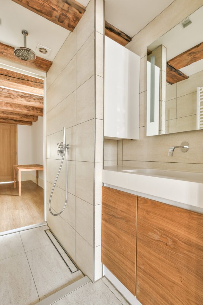 Shower faucet hanging on white tiled wall in light washroom in modern flat